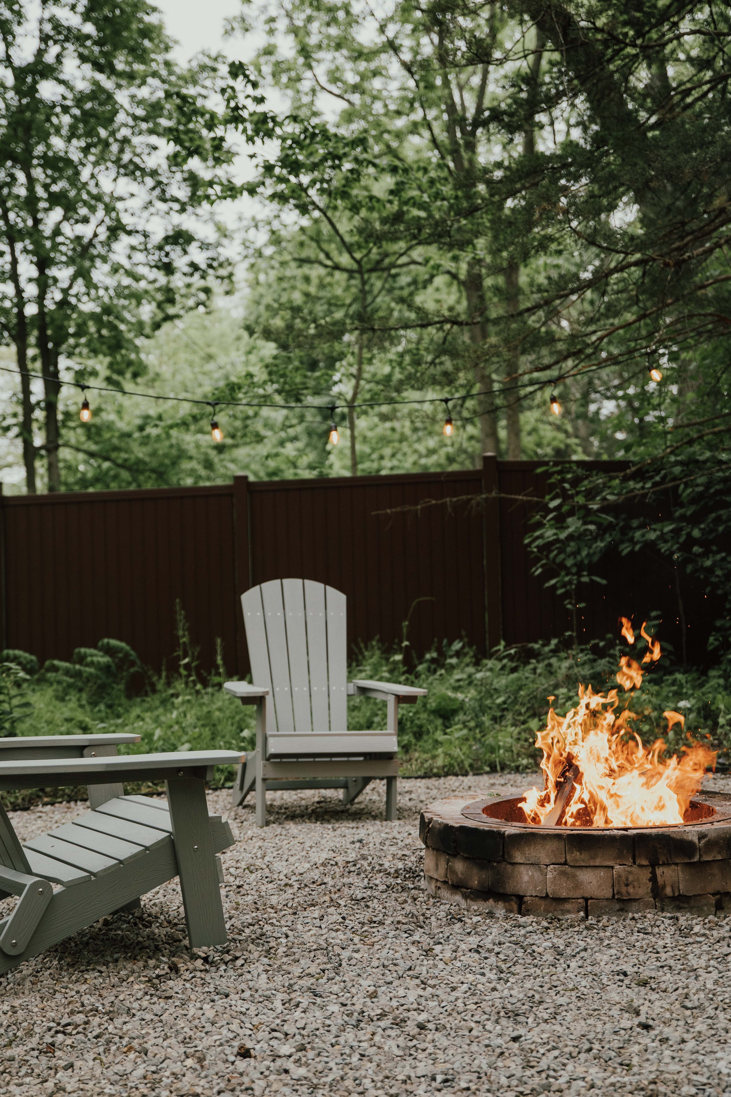 fire pit with campfire burning and forest in backgrounds with Adirondack chairs