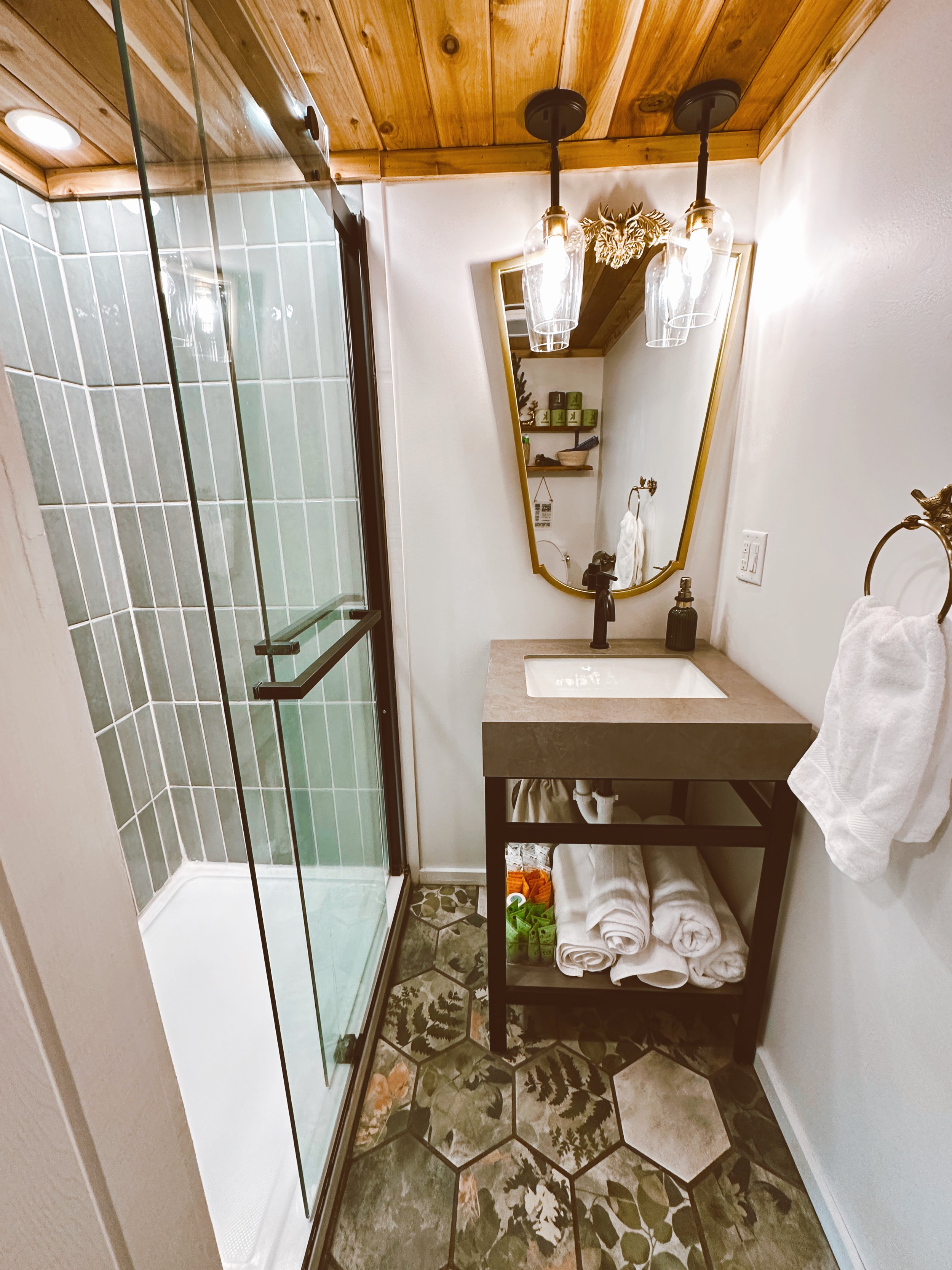 forest bathroom with teal blue tile shower and forest tile hexagon floor